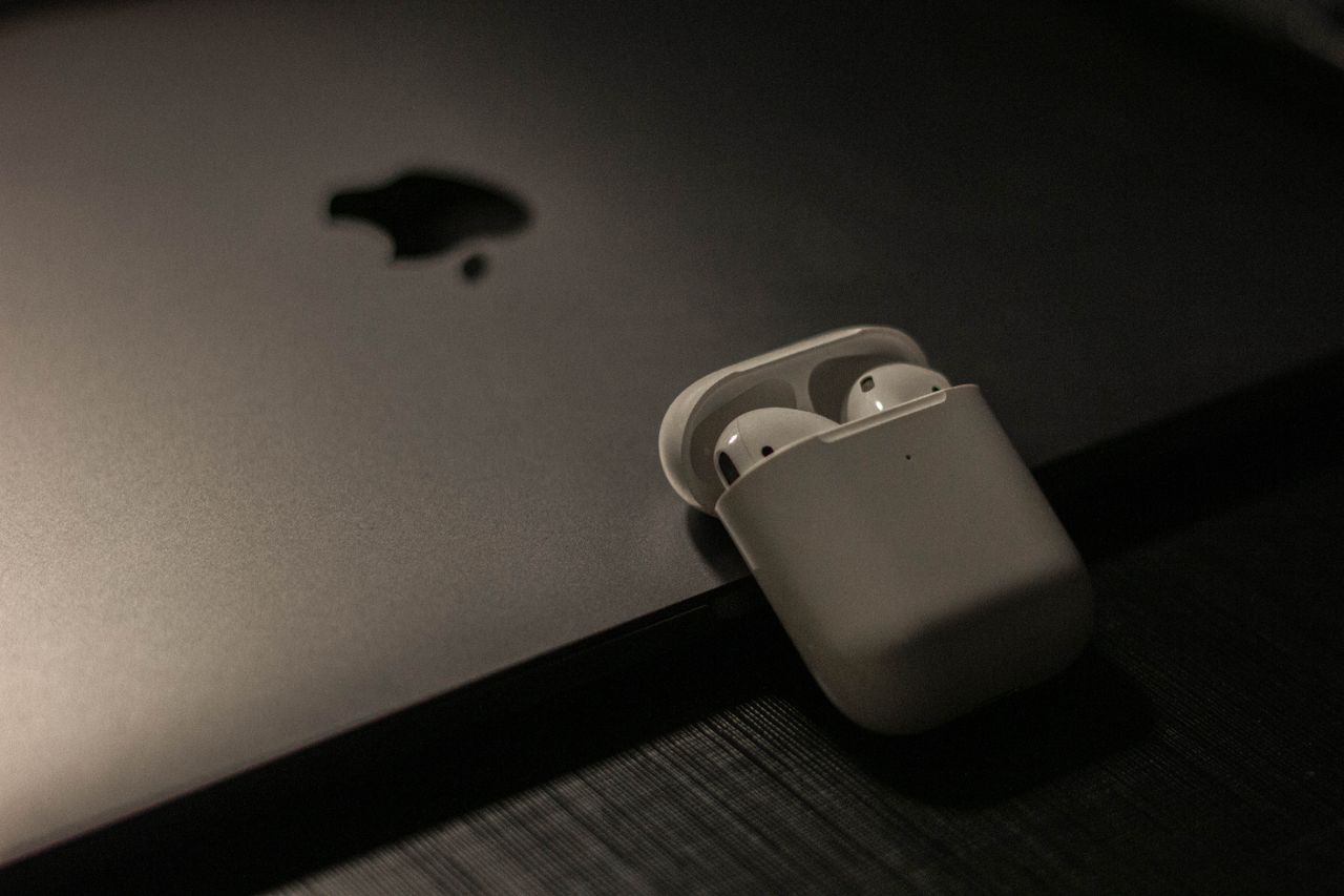 our-experience Sleek wireless earbuds in a case resting on a laptop surface, showcasing modern technology.