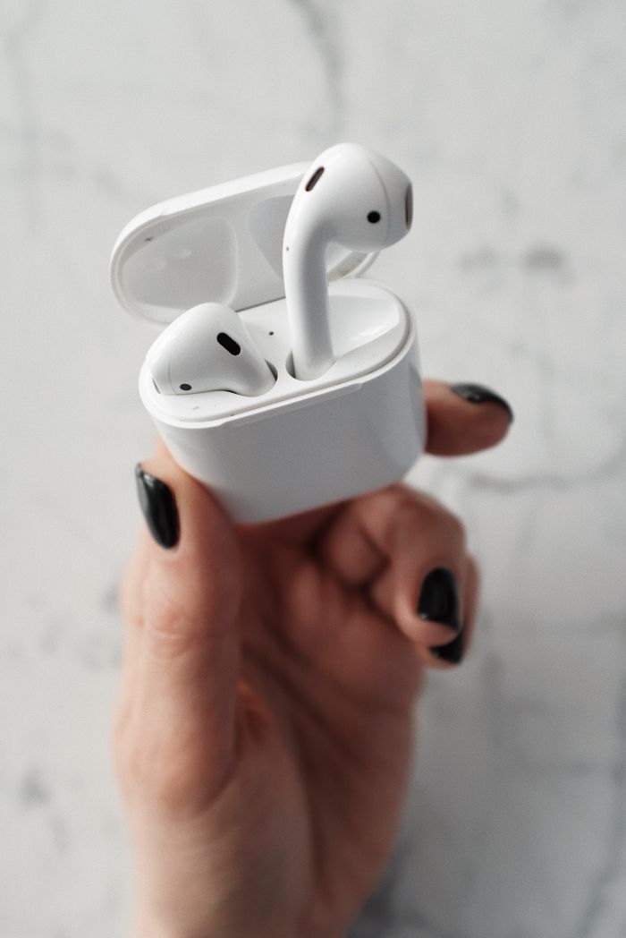 ours-journey Close-up of sleek wireless earbuds in a hand, showcasing modern technology.