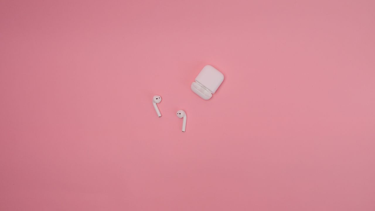 about-img Minimalist image of white wireless earbuds and case on a pink background.